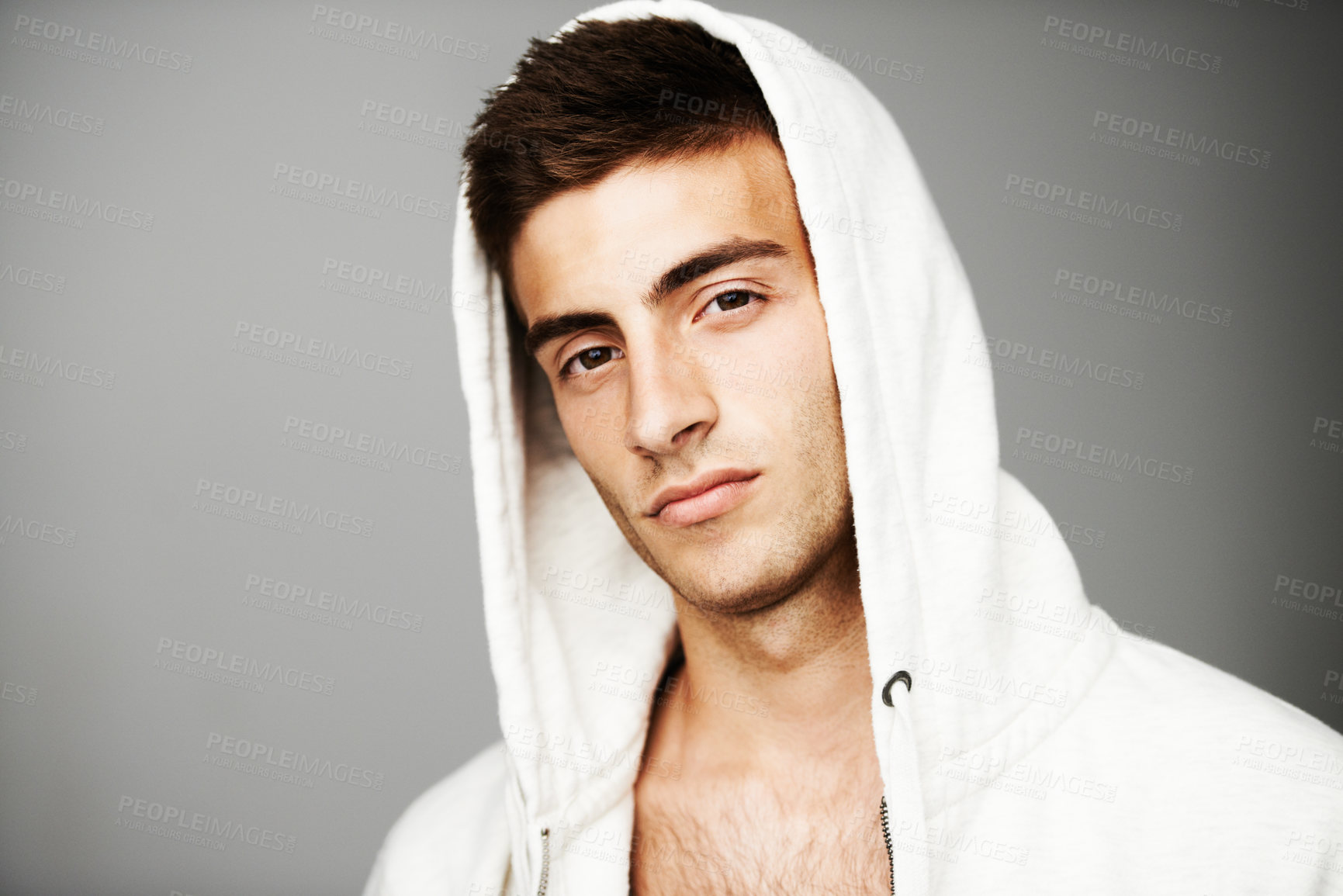 Buy stock photo Confident, portrait and man in hoodie for fashion isolated on a gray background. Serious young person, face of model and streetwear clothes, casual and cool facial expression in Spain on mockup space