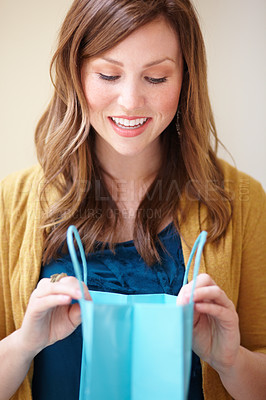 Buy stock photo Cropped shot of an attractive young woman looking happily into a shopping bag