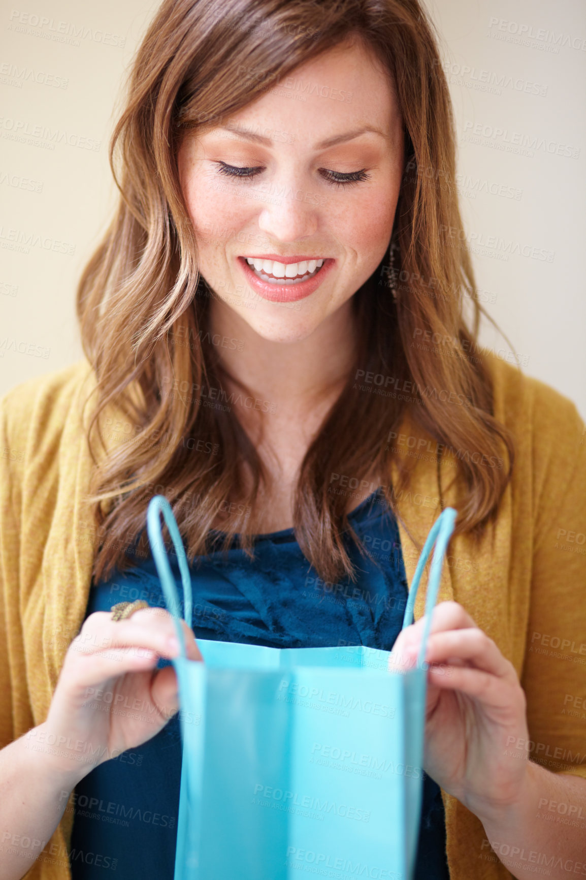 Buy stock photo Cropped shot of an attractive young woman looking happily into a shopping bag