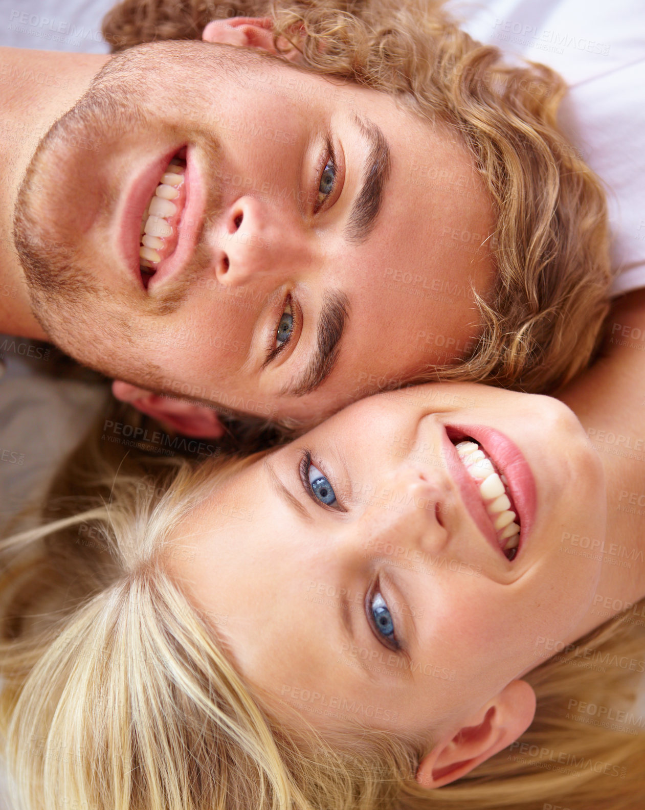 Buy stock photo Portrait, love and smile with a couple on bed in their home together from above to relax while bonding. Face, happy or romantic with a young man and woman in the bedroom of their apartment closeup