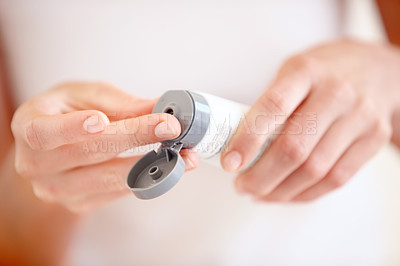 Buy stock photo Cropped image of a young woman putting moisturizer onto her finger