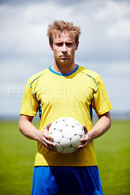 Buy stock photo Shot of a determined looking soccer player holding a soccer ball outdoors