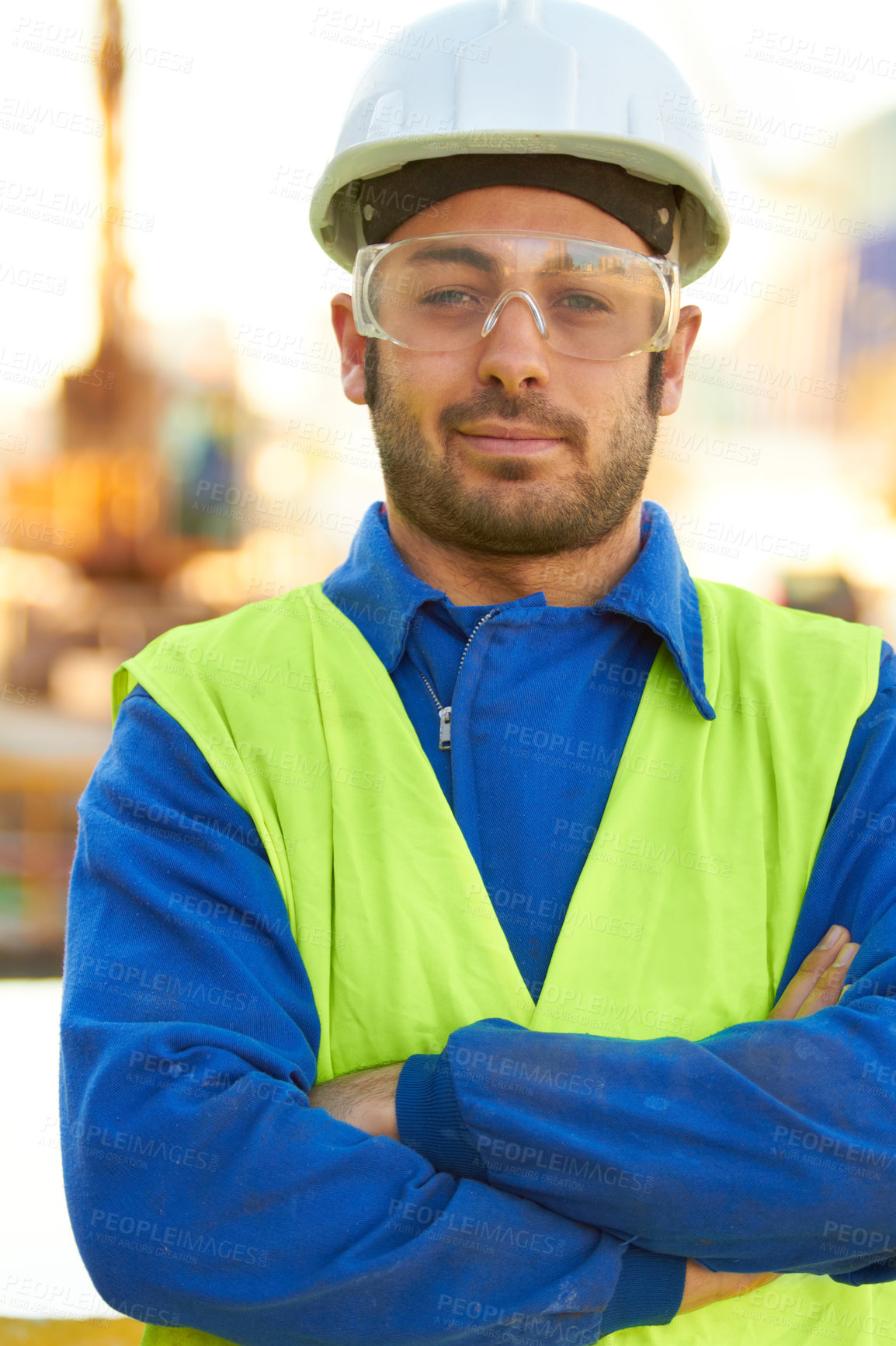 Buy stock photo A stern construction working wearing protective glasses and crossing his arms