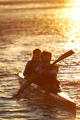 Buy stock photo A shot of two young people on a kayak at sunset