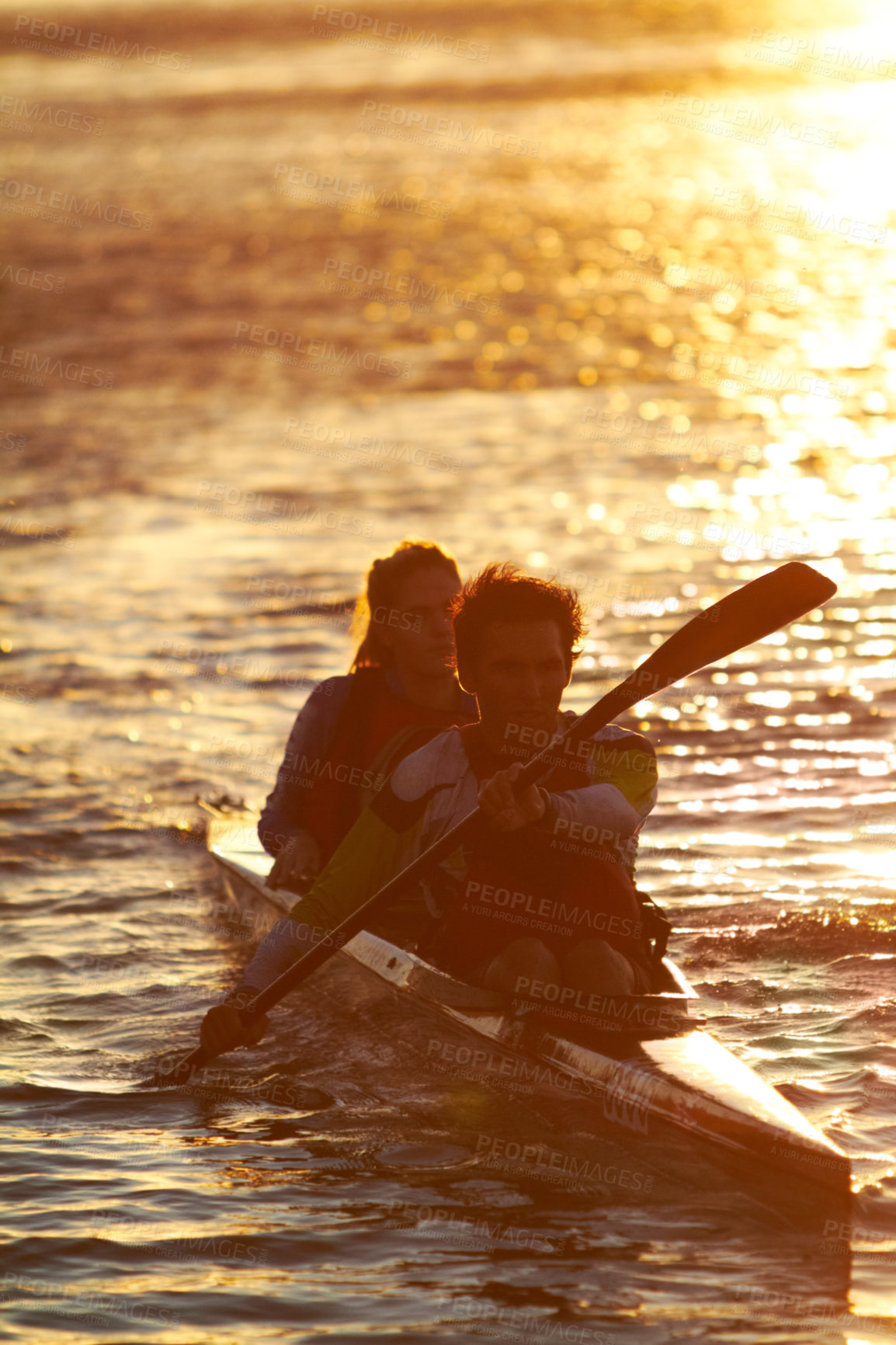 Buy stock photo A shot of two young people on a kayak at sunset