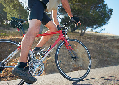 Buy stock photo Cropped shot of a cyclist riding uphill on a rural road