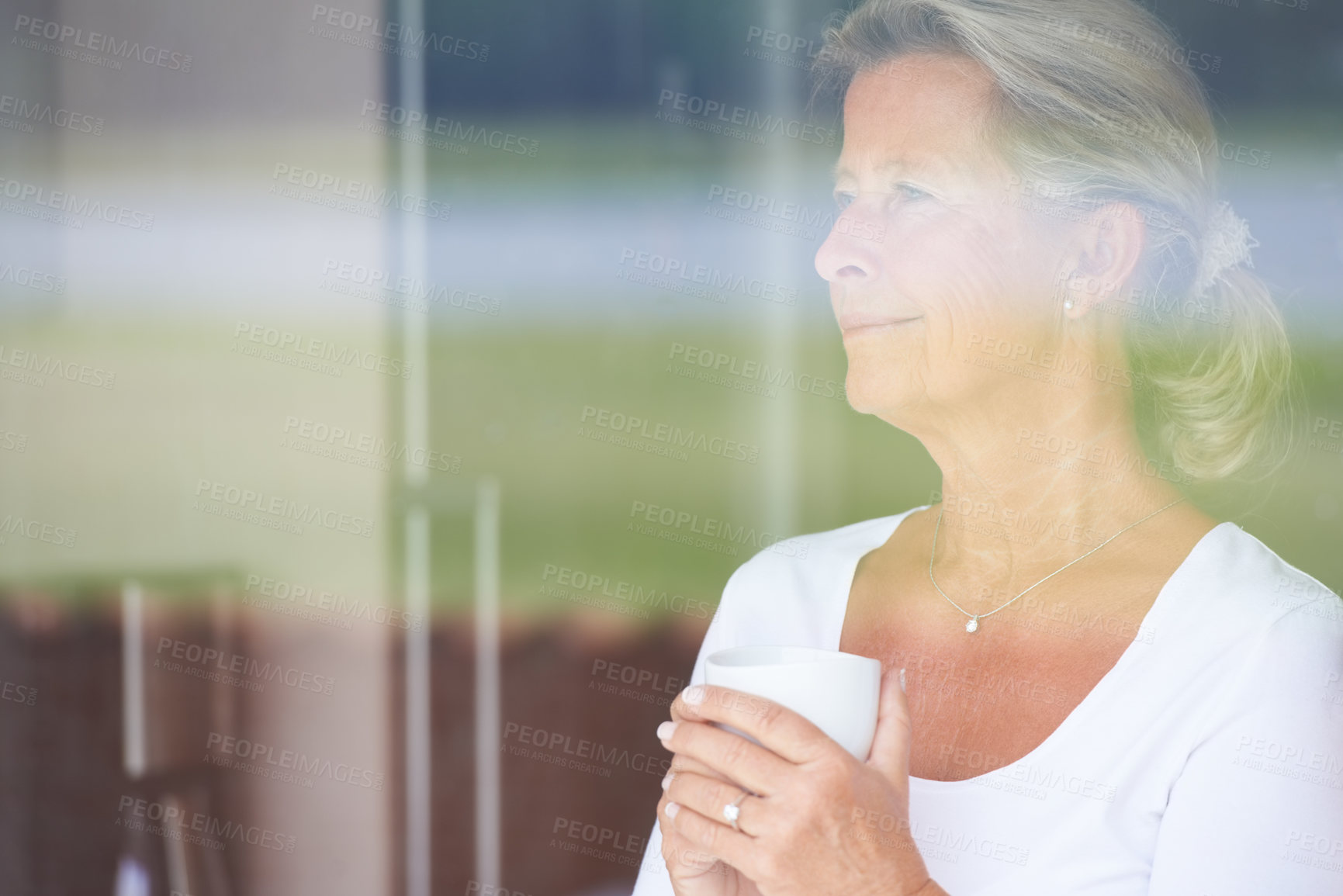 Buy stock photo A thoughtful senior woman looking out of her window while enjoying some coffee