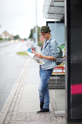 Buy stock photo Man, journey and bus stop with map, travel and adventure by commute, transportation and planning for trip. Male person, information and guide for direction, navigation and vacation or earphones 