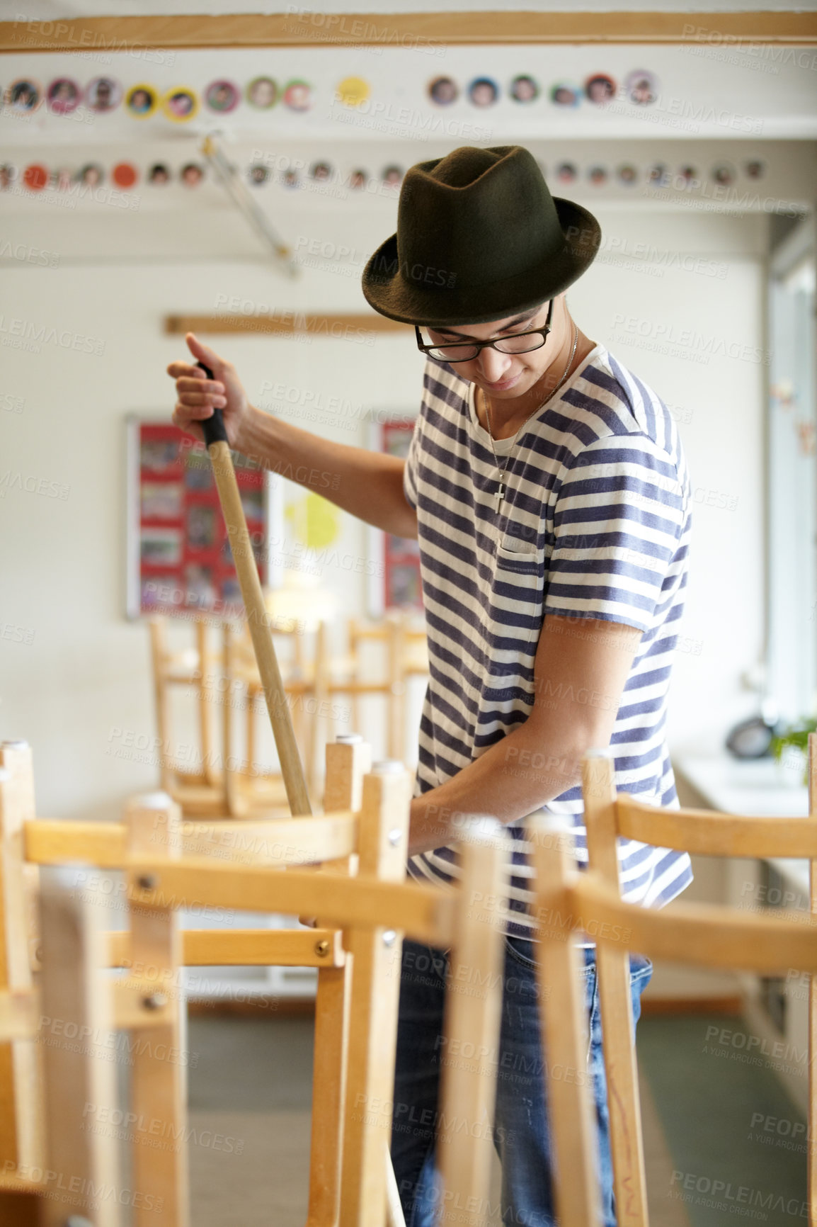 Buy stock photo Man, cleaning and teacher in class at school sweeping floor with dirt, mess or furniture in afternoon or morning. Classroom, broom or janitor clean mud from space for sanitary, maintenance or hygiene