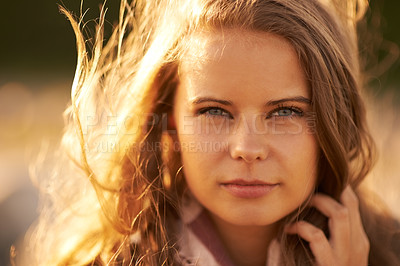 Buy stock photo Serious, woman and portrait in nature at sunset in autumn, spring or environment in summer. Calm, face and girl relax with hair in the wind with golden, sunshine and light at sunrise in morning