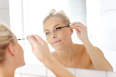 Buy stock photo A beautiful young woman applying mascar in the mirror
