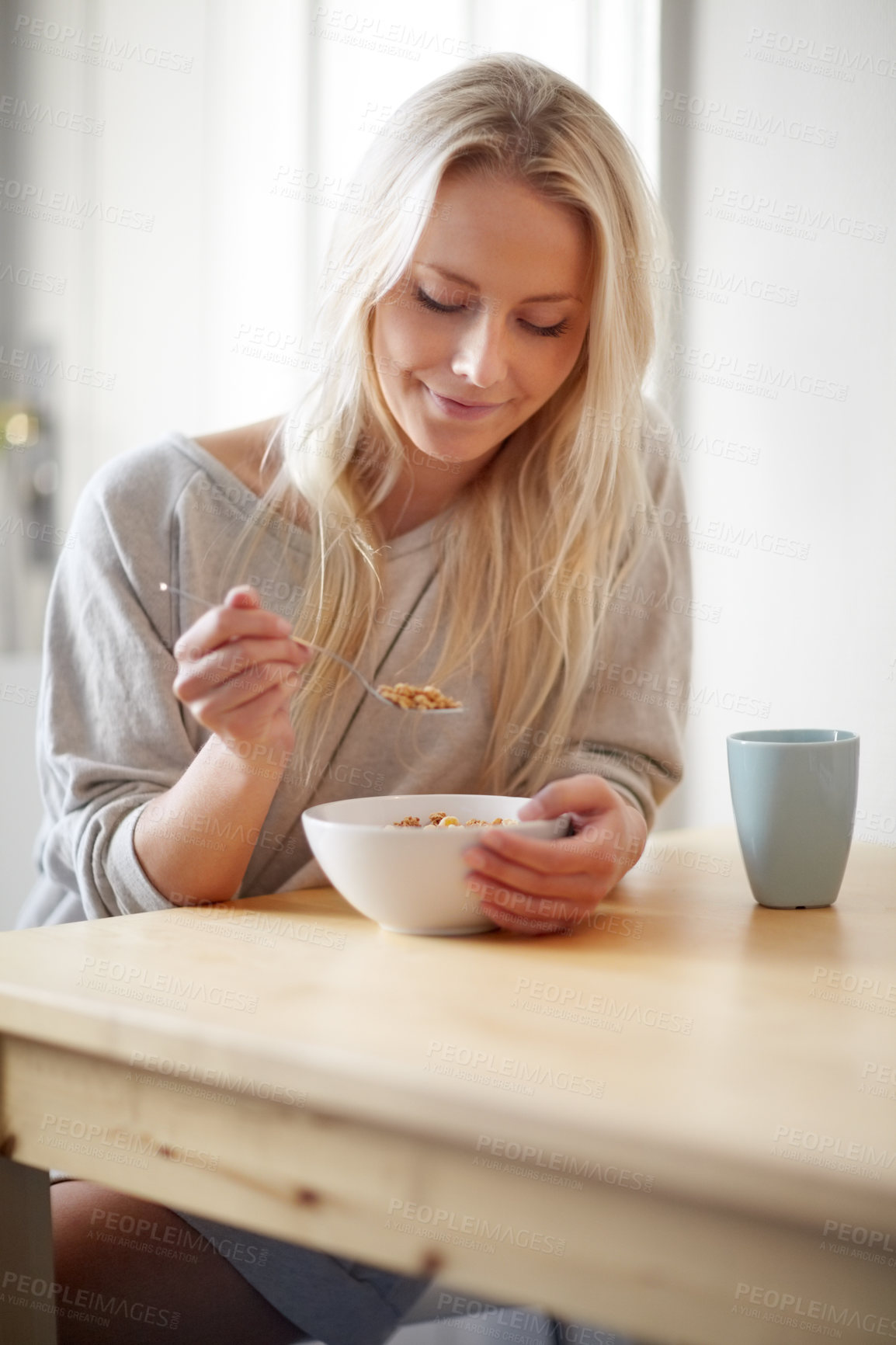 Buy stock photo A gorgeous young woman enjoying her breakfast with a cup of coffee