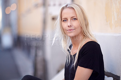 Buy stock photo Portrait of a beautiful young woman sitting on a bench on the street
