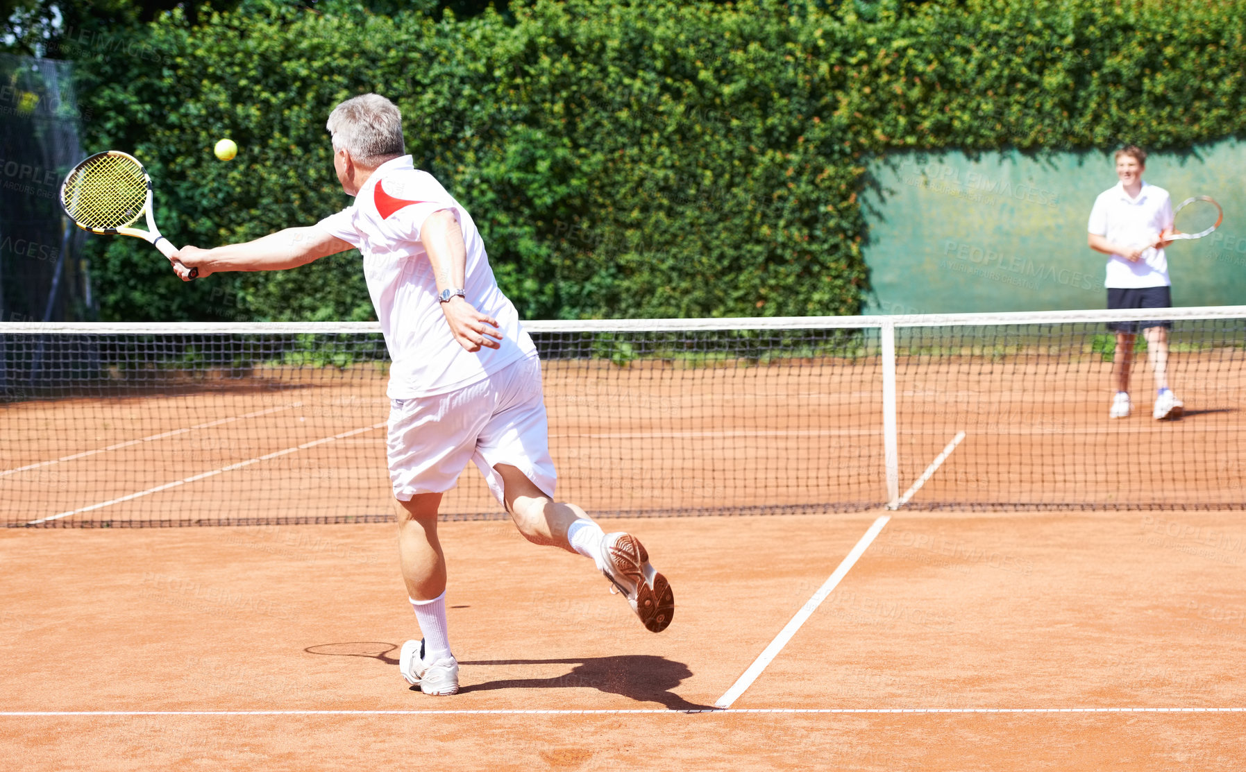Buy stock photo A father and son playing tennis on a clay court