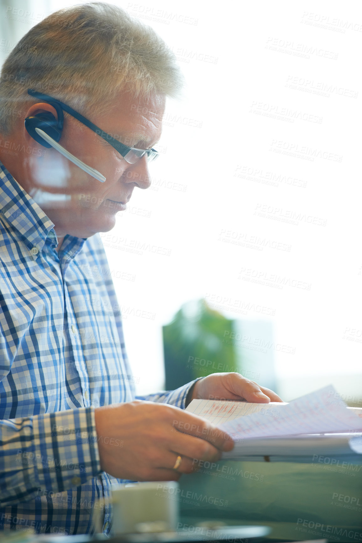 Buy stock photo Man, paperwork and headset for communication in office for career in telesales, customer care or tech support. Mature agent, call centre and document for reading, review or report for consumer growth