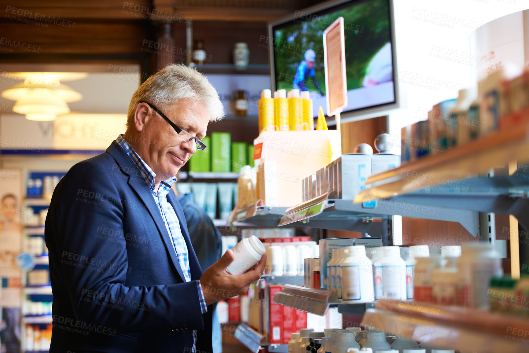 Buy stock photo Shot of a senior man looking for medication in a pharmacy