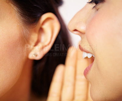 Buy stock photo Cropped view of a young woman telling a secret to a friend