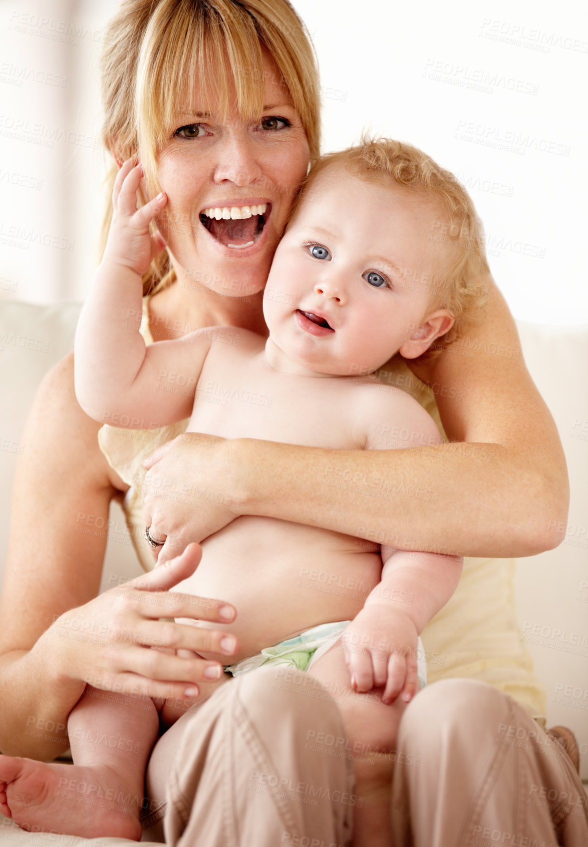 Buy stock photo Laughing mother holding her baby boy on her lap