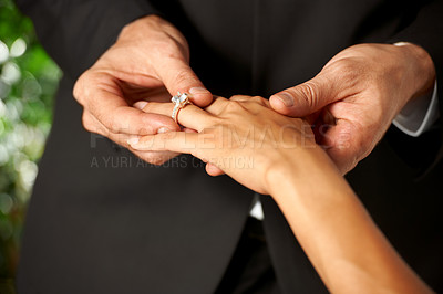 Buy stock photo Cropped view of a groom slipping a ring on to his bride's finger