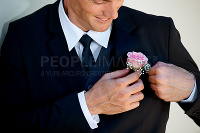 Buy stock photo Cropped image of a happy groom adjusting his boutonniere before the wedding begins
