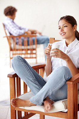 Buy stock photo Beautiful woman looking away happily with a man relaxing in the backgroun
