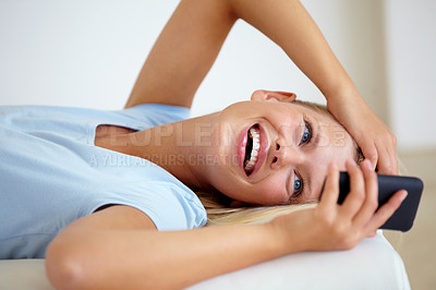 Buy stock photo Young woman lying on the sofa at home and sending a text using her mobile