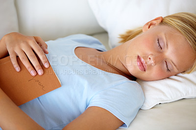 Buy stock photo Young woman fast asleep on the couch after doing some reading