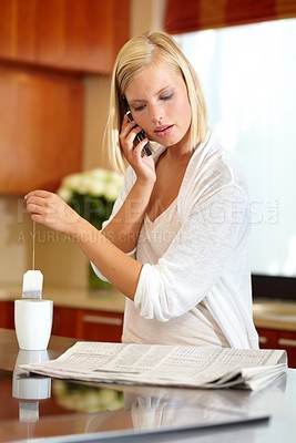 Buy stock photo Woman, newspaper and phone call in kitchen, communication and information or headlines. Female person, smartphone and conversation or chat, making tea and hot drink for breaking news or newsletter 