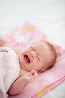 Buy stock photo Shot of a wailing baby lying on a blanket