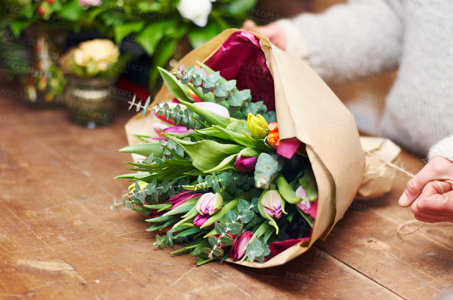 Buy stock photo Cropped shot of a pretty floral bouquet being completed on a wooden counter top