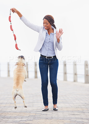 Buy stock photo A beautiful african woman playing with her dog on the promenade