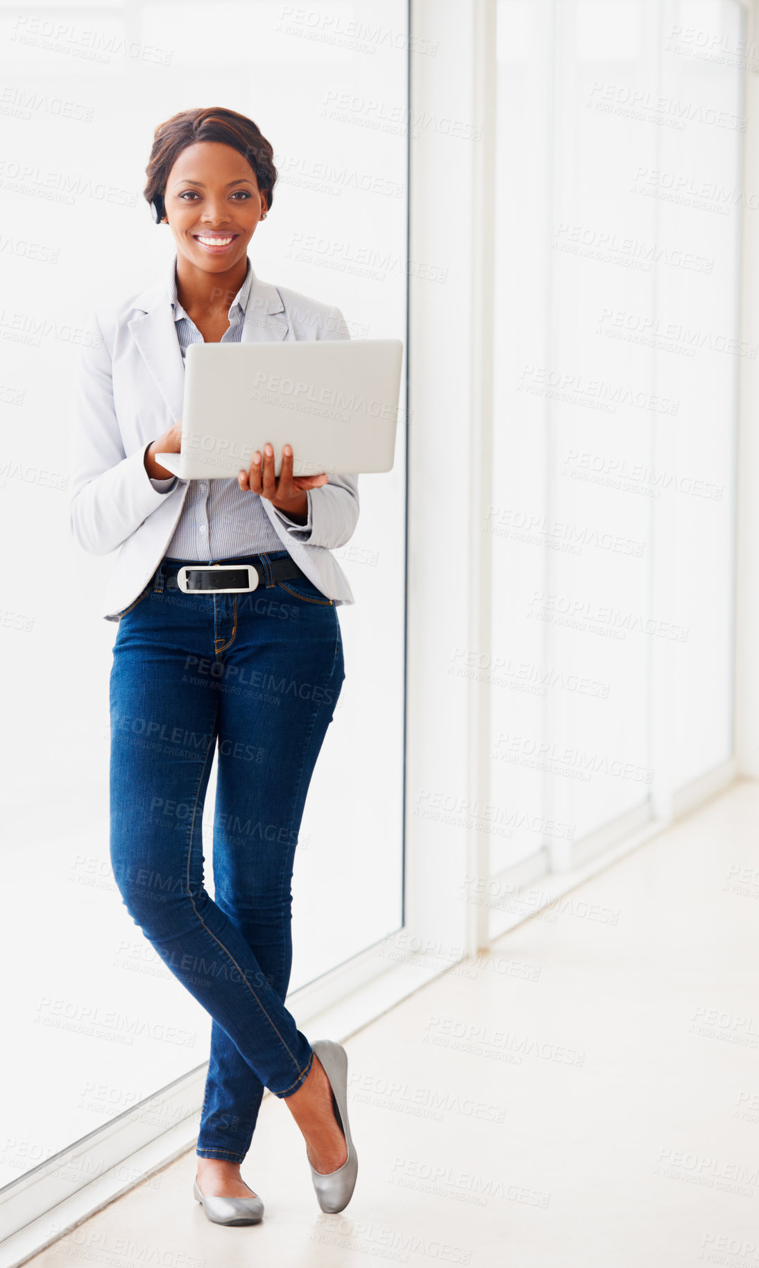 Buy stock photo Black business woman, laptop and portrait by window, smile and typing for proposal, project and pride in workplace. African entrepreneur, computer and happy in hallway for project management on web
