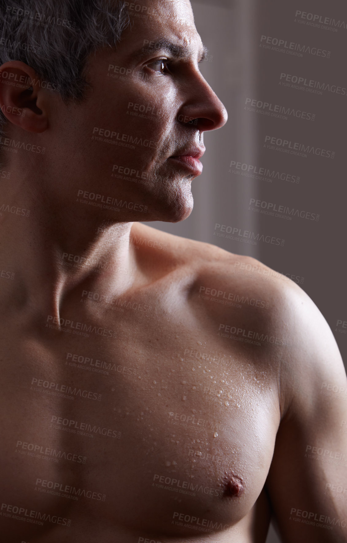 Buy stock photo A darkly lit image of a shirtless man looking away thoughtfully