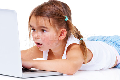 Buy stock photo An adorable little girl looking amazed while lying down using a laptop