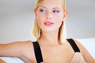 Buy stock photo Gorgeous young blonde woman sitting on a couch looking sideways