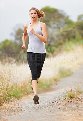 Buy stock photo A young woman running on a dirt road