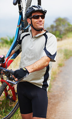 Buy stock photo Shot of a sportsman carrying his mountain bike