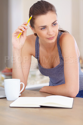 Buy stock photo A beautiful young woman looking thoughtful while writing in a book