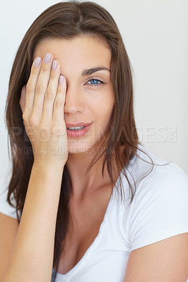 Buy stock photo A pretty young woman covering one of her eyes