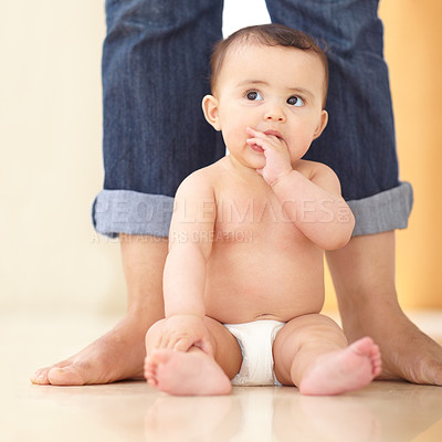 Buy stock photo An adorable baby sitting at her mother's feet