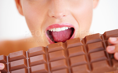 Buy stock photo Cropped view of a young woman biting into a big slab of chocolate
