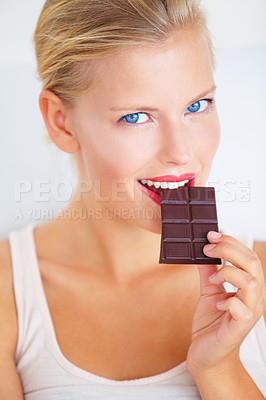 Buy stock photo Smiling young woman enjoying a delicious piece of chocolate