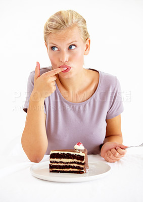 Buy stock photo Young woman tasting the frosting of a delicious piece of chocolate cake