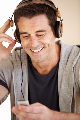 Buy stock photo A handsome young man listen to music through his headphones