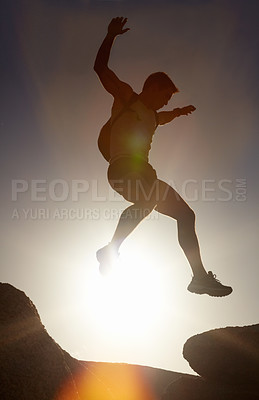 Man, silhouette and jump on rock at sunset with freedom, adventure and challenge on mountain or cliff. Climbing, hill and person with fearless leap in hiking, exercise or energy at with sky in summer