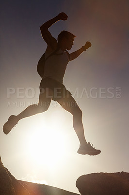 Buy stock photo Man, silhouette and jump on rock at sunset with freedom, adventure and challenge on mountain or cliff. Climbing, hill and person with fearless leap in exercise, sport or energy at with sky in summer