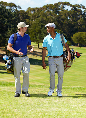 Buy stock photo Shot of two friends talkin on their way to the tee-off