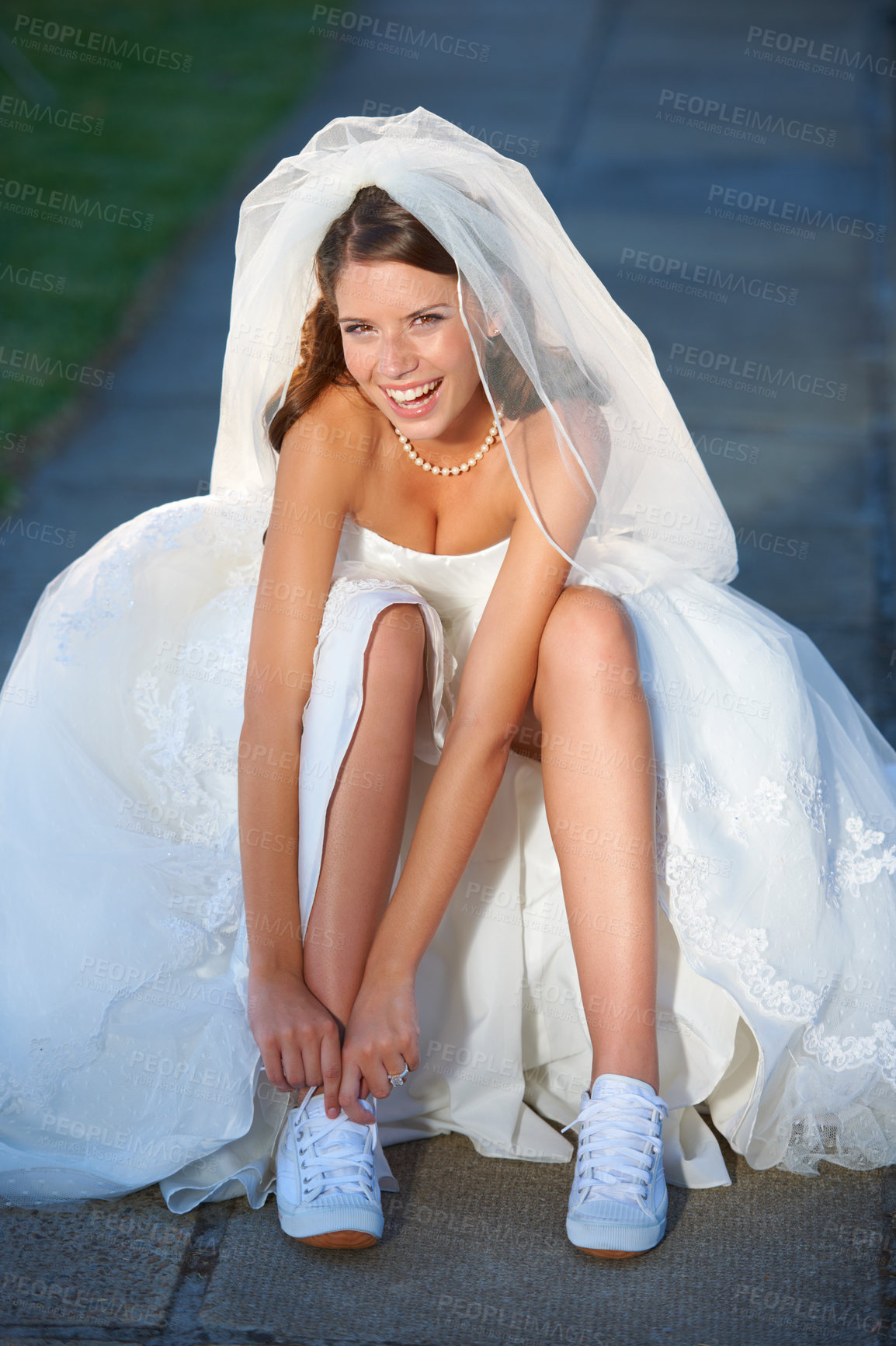 Buy stock photo Fun shot of a young bride taking off running shoes she is wearing under her dress