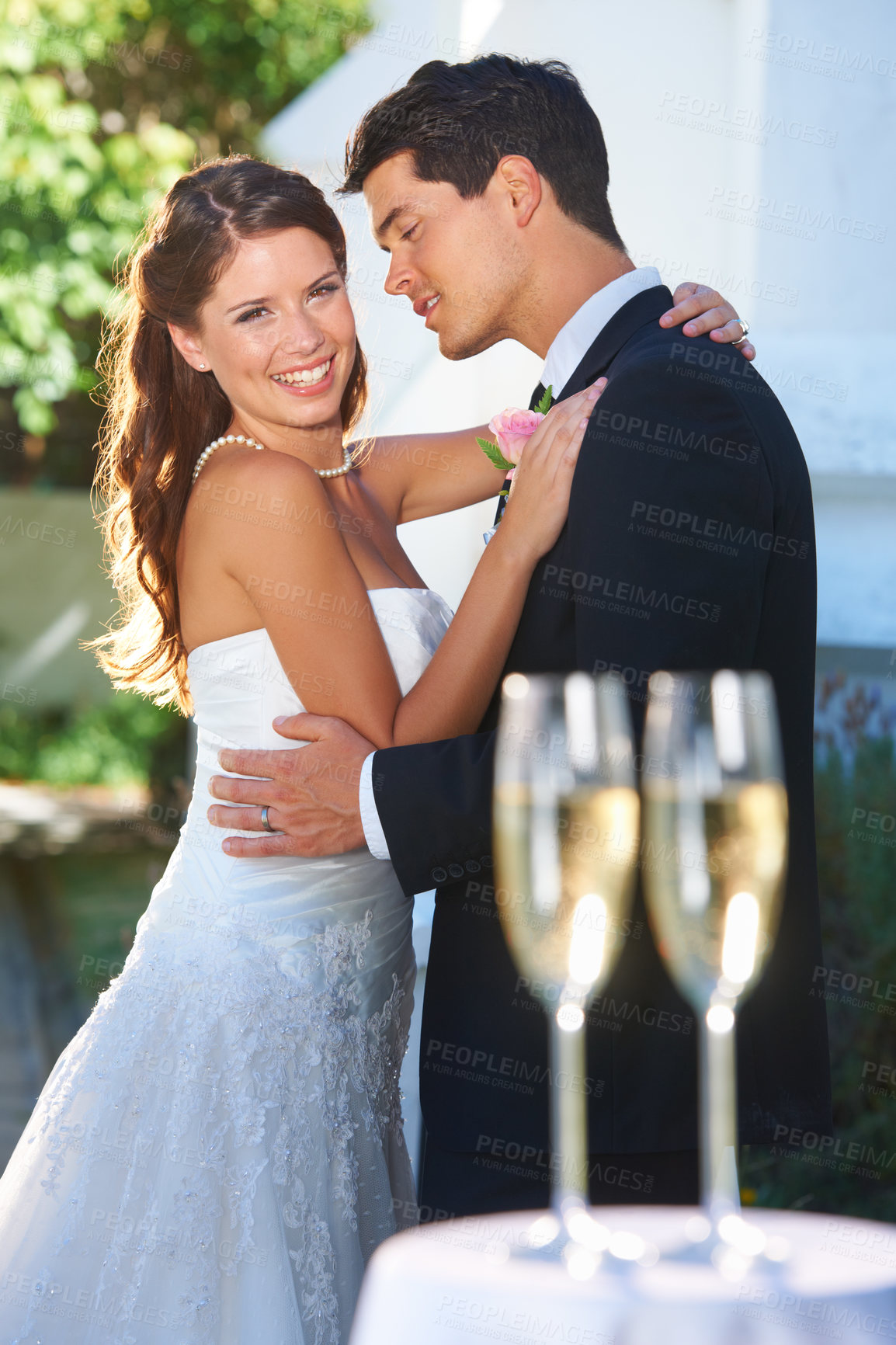 Buy stock photo Happy couple, wedding and hug with champagne glasses in celebration for love, commitment or outdoor marriage. Man hugging woman smile in embrace, affection or support with alcohol at bridal ceremony
