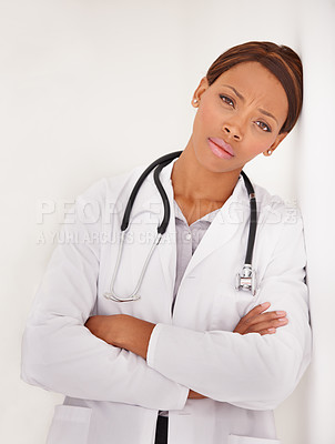 Buy stock photo A serious ethnic female doctor with her head resting against the wall